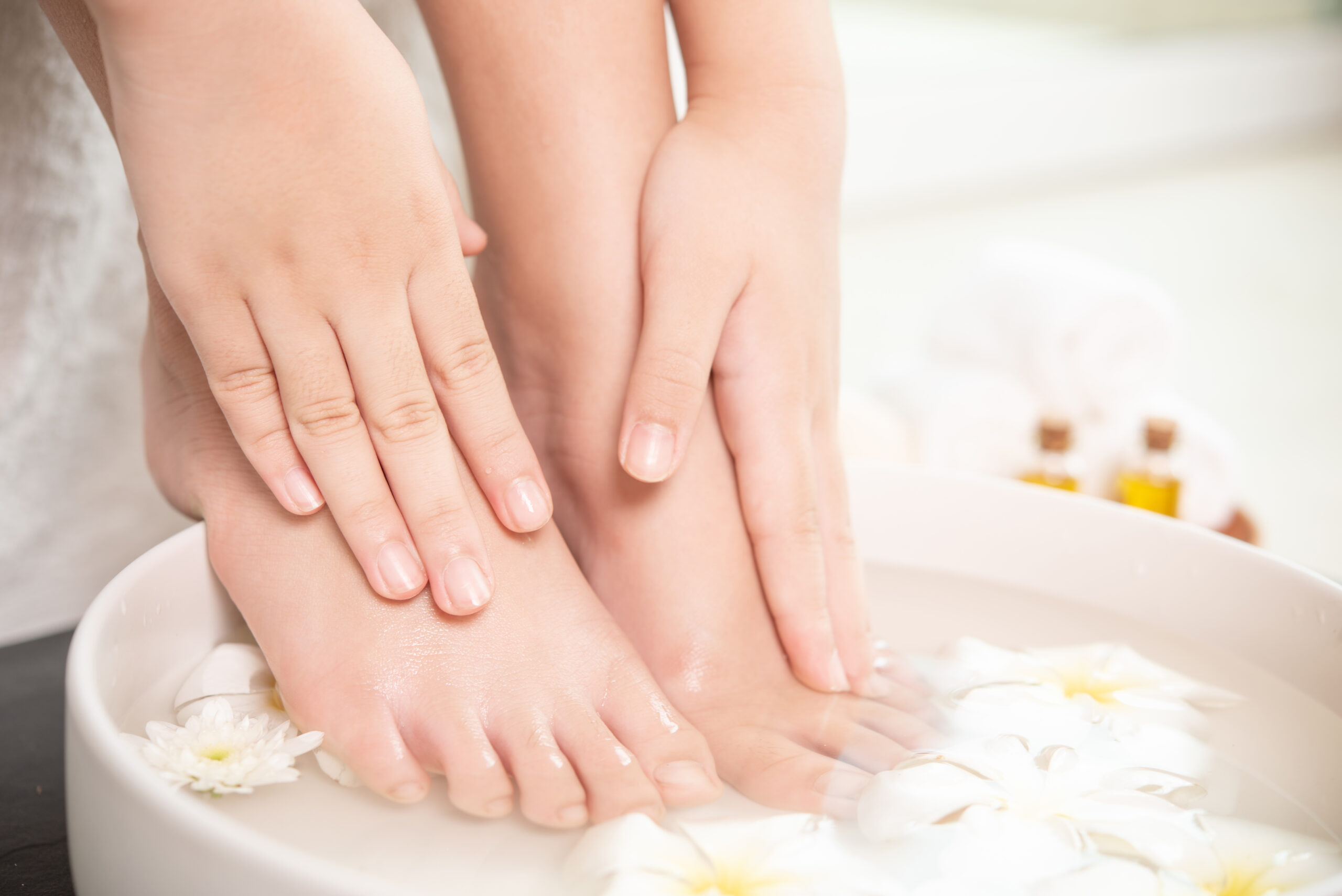 closeup view of woman soaking her hand and feet in dish with wat